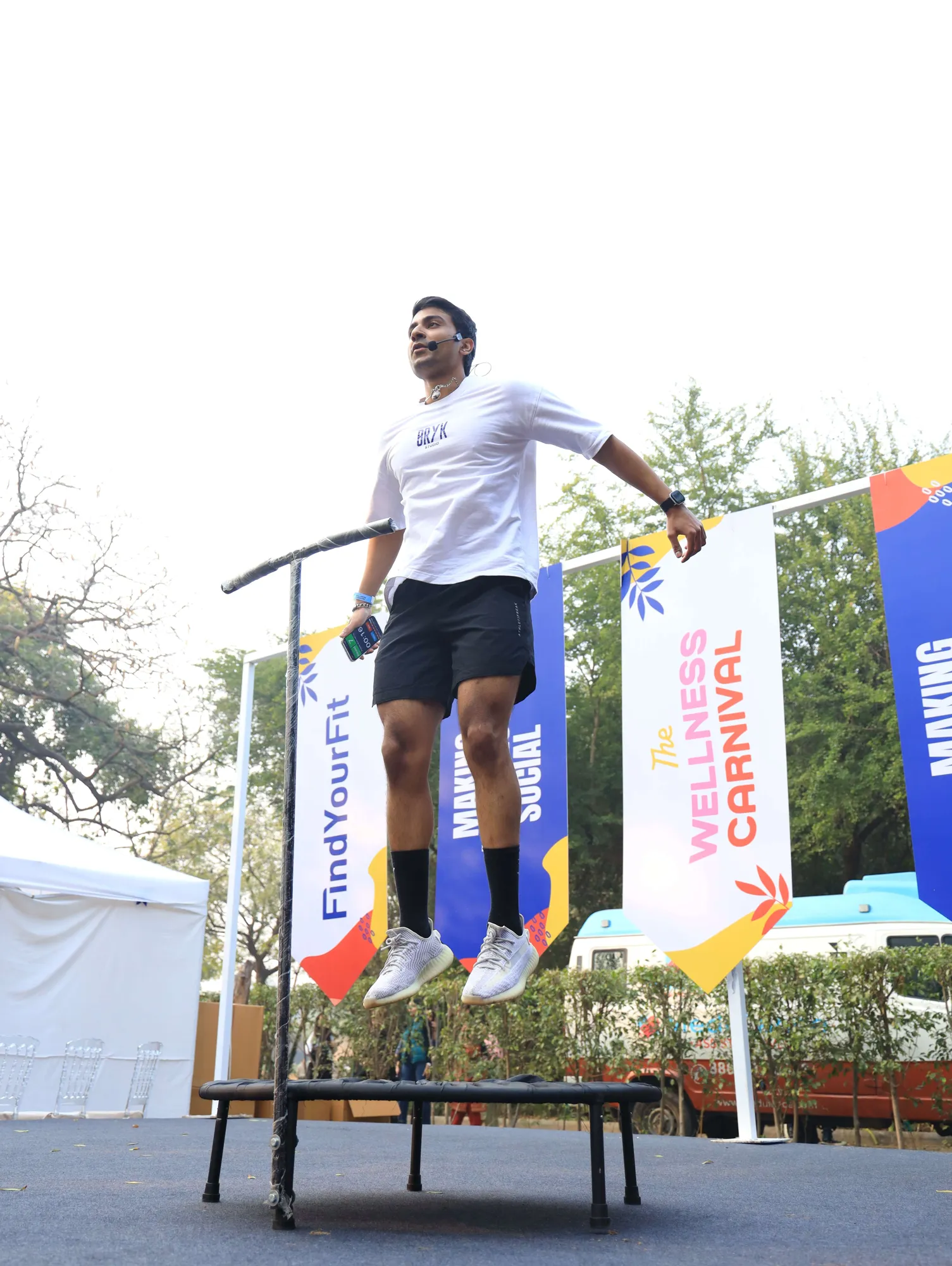 A carnival-goer mid-jump on a rebounder, The Wellness Carnival banner behind them