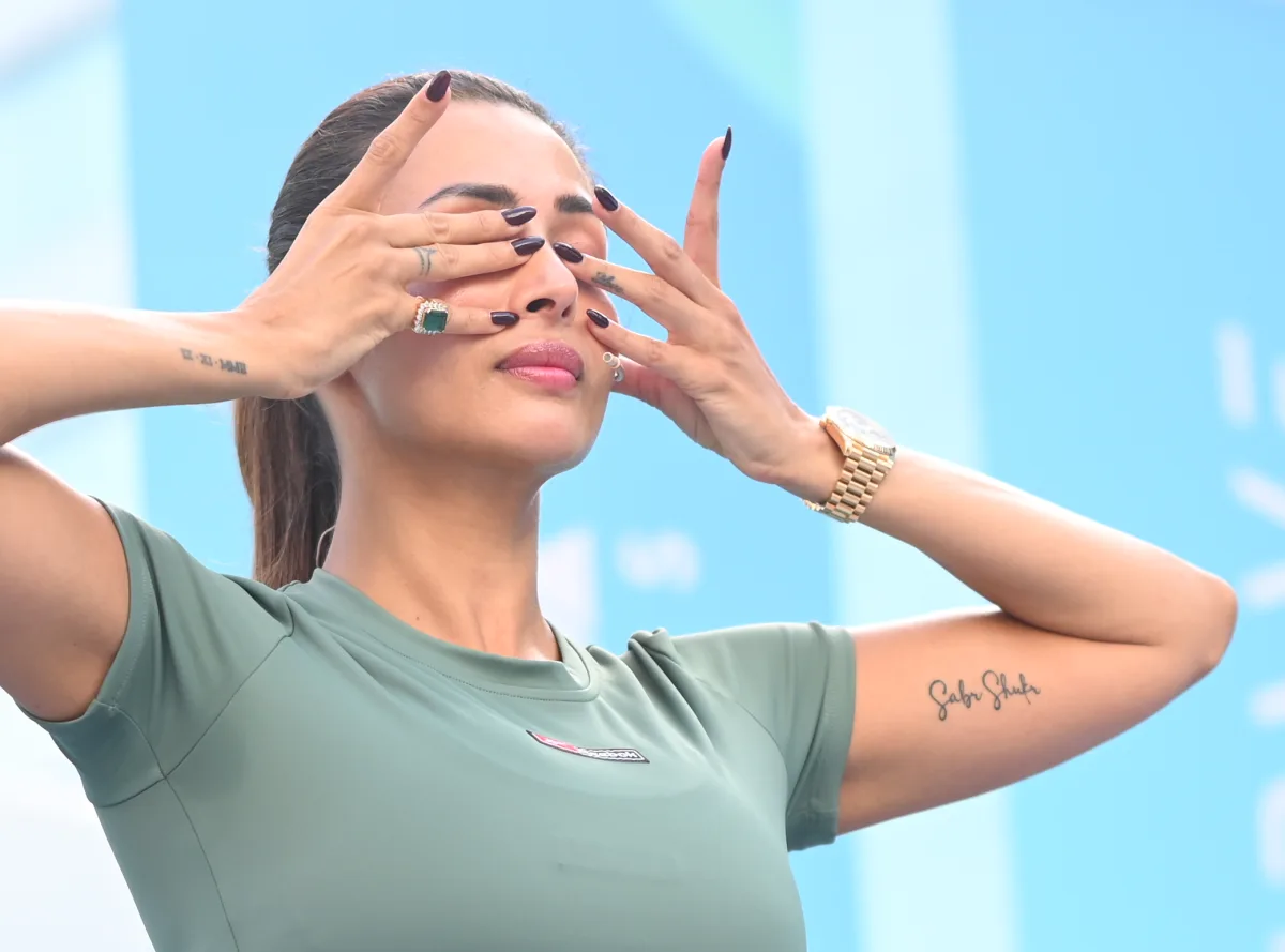 A participant covering her eyes in a breathwork moment among a large seated crowd at a wellness festival